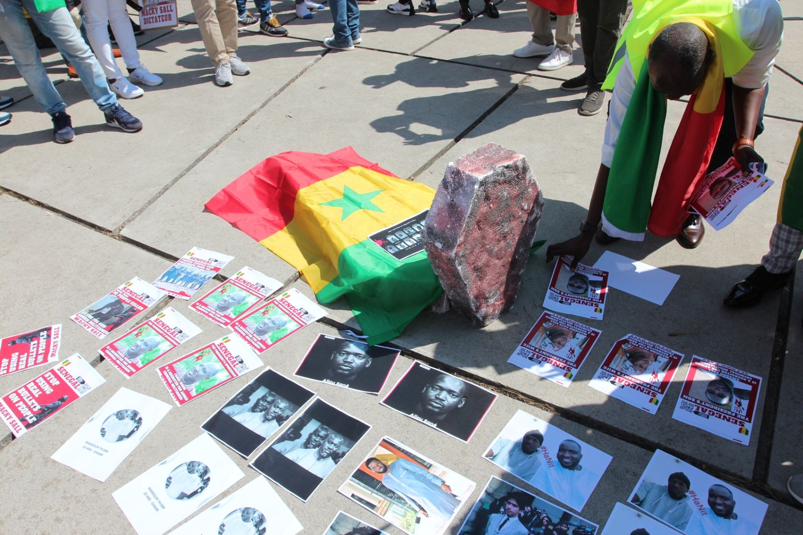 Hommage aux victimes devant la Cour pénale internationale : drapeau du Sénégal et portraits déposés au sol