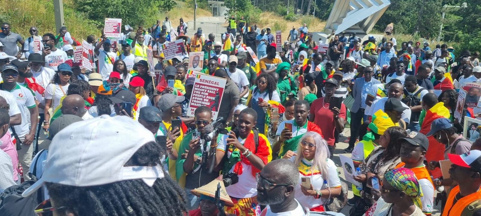 Foule de la diaspora sénégalaise brandissant drapeaux et pancartes lors d'une manifestation